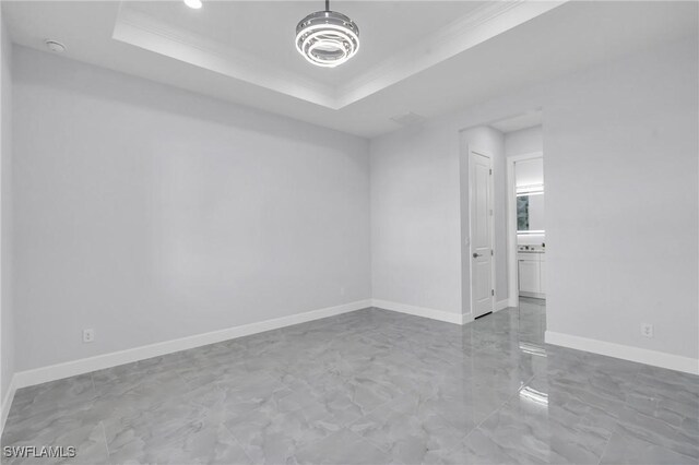 empty room featuring a raised ceiling and ornamental molding