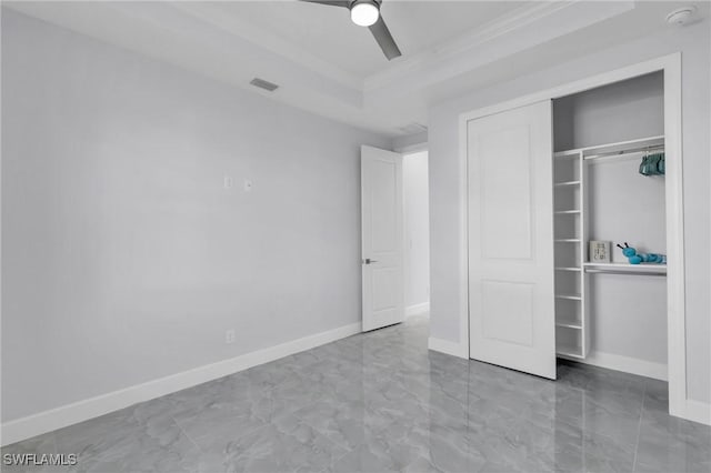 unfurnished bedroom with a raised ceiling, ceiling fan, a closet, and crown molding