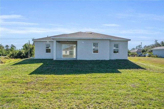 back of property featuring a lawn and ceiling fan