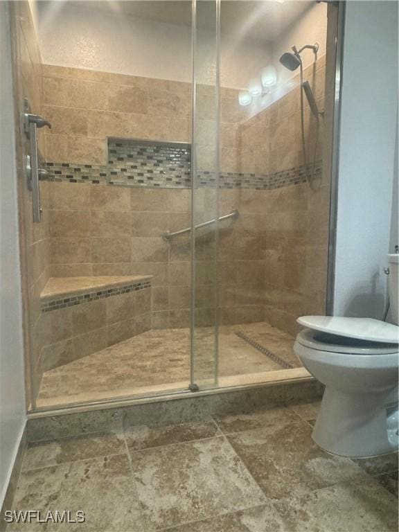 bathroom with a shower with shower door and toilet