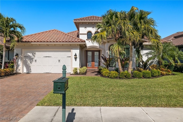 mediterranean / spanish home with a front yard, french doors, and a garage