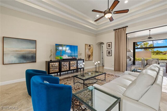 living room featuring a towering ceiling, a raised ceiling, ceiling fan, and ornamental molding