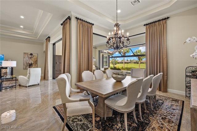 dining area with ornamental molding, a notable chandelier, and a tray ceiling