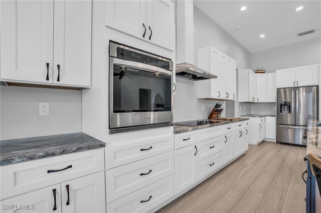 kitchen featuring white cabinetry, light wood-type flooring, ceiling fan, dark stone counters, and appliances with stainless steel finishes