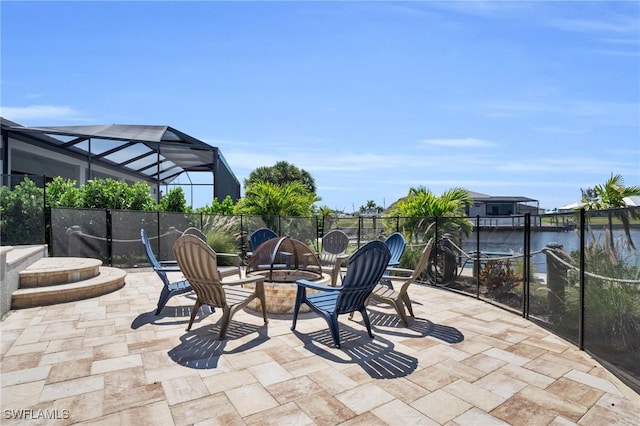 view of patio with an outdoor fire pit, a water view, and glass enclosure