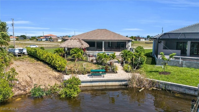 rear view of property featuring a lanai, a yard, and a water view