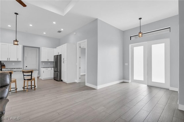 kitchen with white cabinets, a breakfast bar, hanging light fixtures, and stainless steel fridge