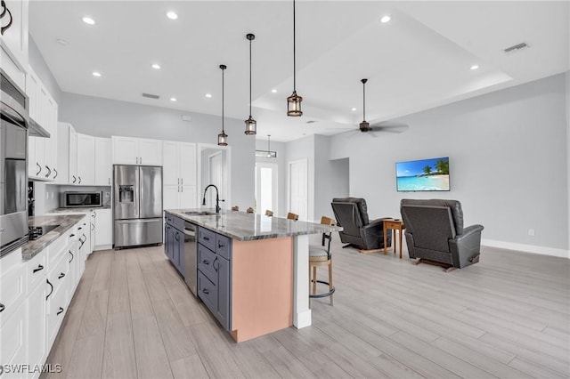 kitchen with a large island, white cabinetry, dark stone counters, and appliances with stainless steel finishes