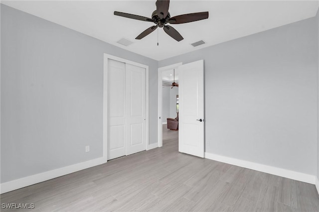 unfurnished bedroom featuring ceiling fan, light hardwood / wood-style floors, and a closet