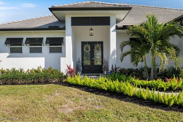 entrance to property with a yard and french doors