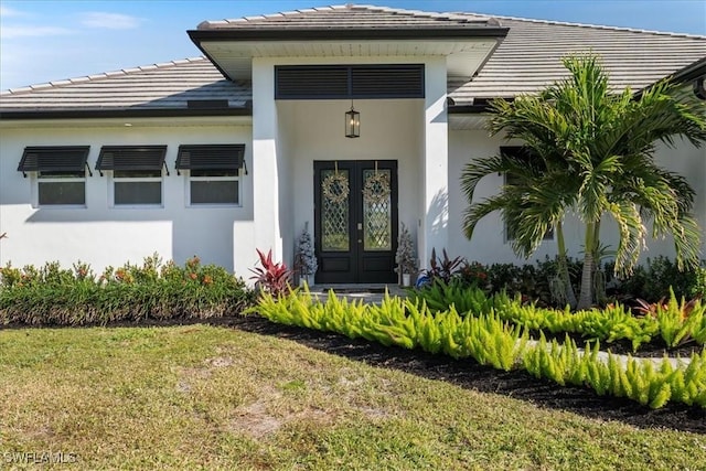 entrance to property featuring a yard and french doors