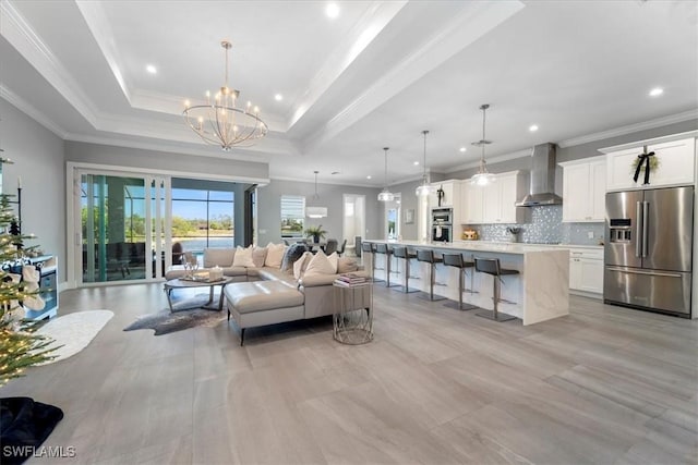 living room featuring a tray ceiling, crown molding, and a notable chandelier