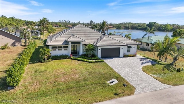 single story home with a water view, a front lawn, and a garage