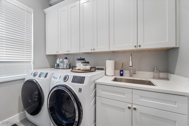 clothes washing area with cabinets, washer and dryer, and sink