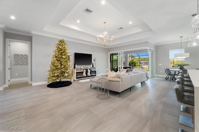 living room with a tray ceiling, ornamental molding, and an inviting chandelier