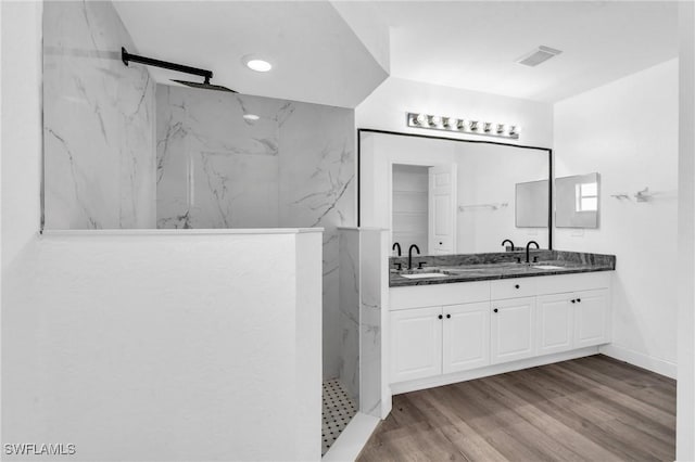 bathroom featuring hardwood / wood-style flooring, vanity, and tiled shower