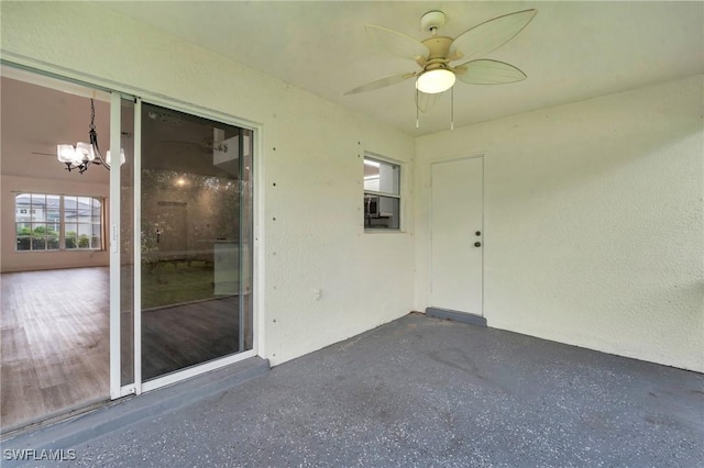 unfurnished sunroom featuring ceiling fan with notable chandelier