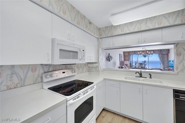 kitchen with light wood-type flooring, white appliances, sink, white cabinets, and a chandelier