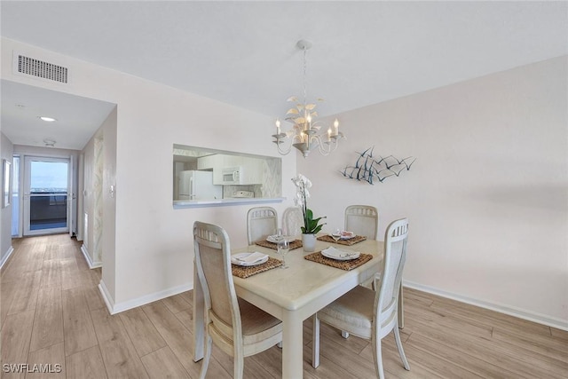 dining space featuring an inviting chandelier and light wood-type flooring