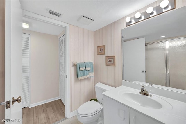 bathroom featuring hardwood / wood-style floors, vanity, toilet, and a shower with door