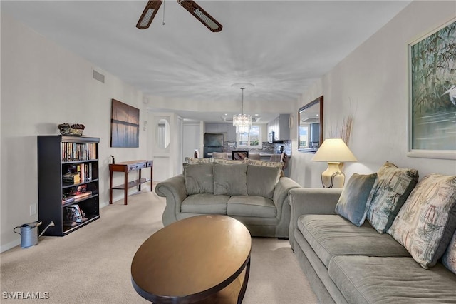 living room featuring ceiling fan with notable chandelier and light carpet