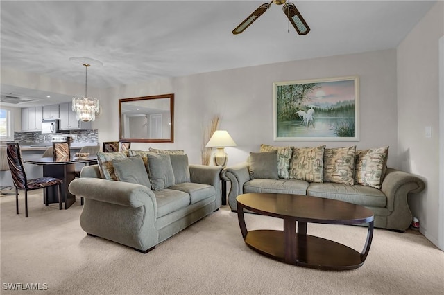 carpeted living room with ceiling fan with notable chandelier