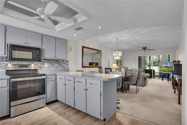 kitchen with kitchen peninsula, backsplash, light hardwood / wood-style floors, hanging light fixtures, and stainless steel range with electric cooktop