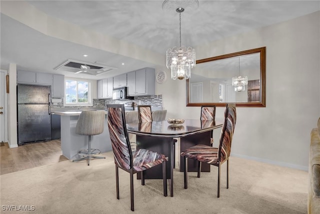 dining room with ceiling fan with notable chandelier, a raised ceiling, and light colored carpet