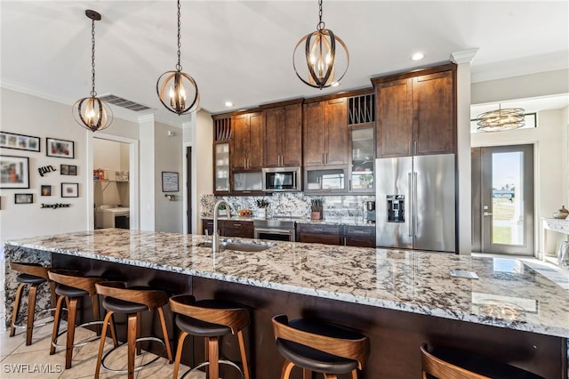 kitchen with backsplash, sink, ornamental molding, appliances with stainless steel finishes, and decorative light fixtures