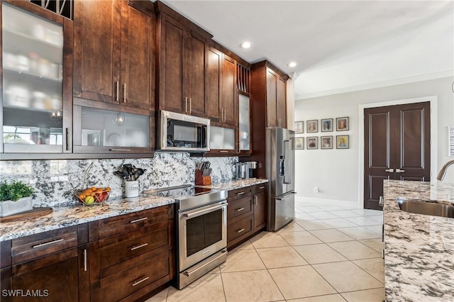 kitchen featuring sink, stainless steel appliances, light stone counters, decorative backsplash, and ornamental molding