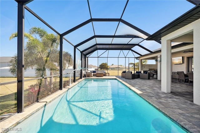 view of pool featuring an outdoor hangout area, glass enclosure, a patio, and ceiling fan