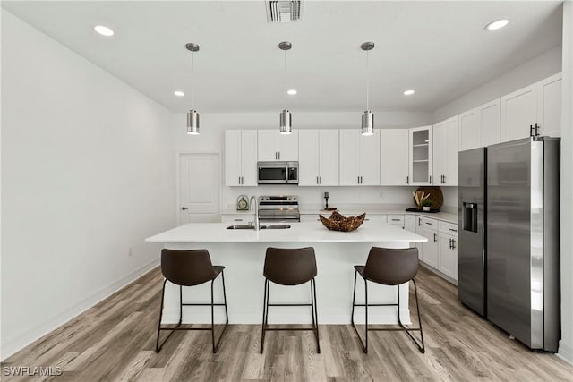 kitchen with pendant lighting, light wood-type flooring, and appliances with stainless steel finishes