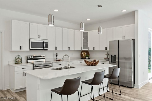 kitchen featuring sink, light hardwood / wood-style flooring, an island with sink, white cabinets, and appliances with stainless steel finishes