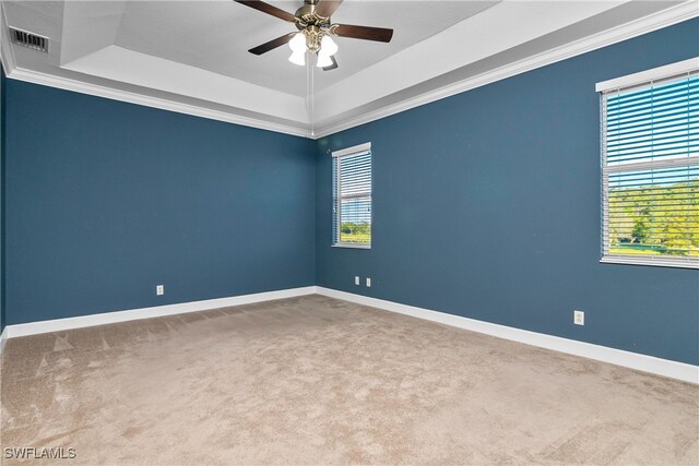 carpeted spare room with a tray ceiling, ceiling fan, and crown molding