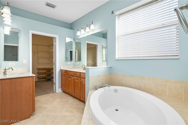 bathroom featuring tile patterned floors, tiled bath, and vanity