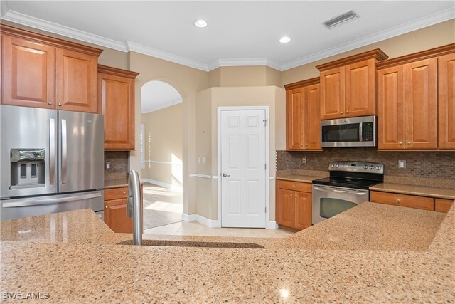 kitchen with crown molding, sink, light stone counters, and appliances with stainless steel finishes