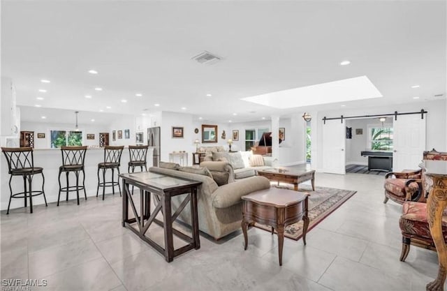 living room with a barn door and light tile patterned floors