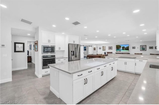 kitchen featuring light tile patterned flooring, billiards, a kitchen island, white cabinetry, and stainless steel appliances