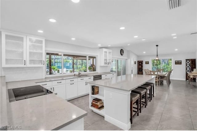 kitchen with white cabinets, a kitchen island, a wealth of natural light, and vaulted ceiling