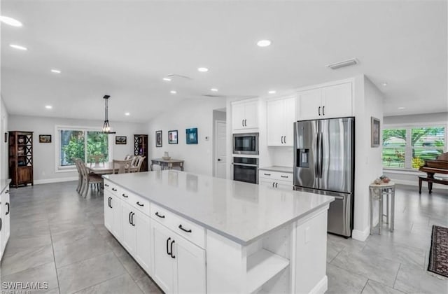 kitchen with a kitchen island, white cabinets, a healthy amount of sunlight, and appliances with stainless steel finishes