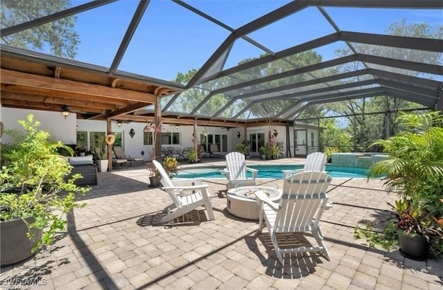 view of patio with glass enclosure, a swimming pool with hot tub, and an outdoor fire pit