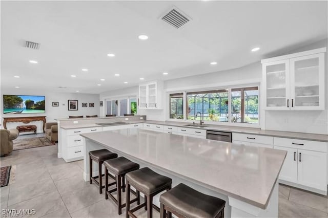 kitchen featuring kitchen peninsula, a kitchen island, white cabinetry, and a breakfast bar area