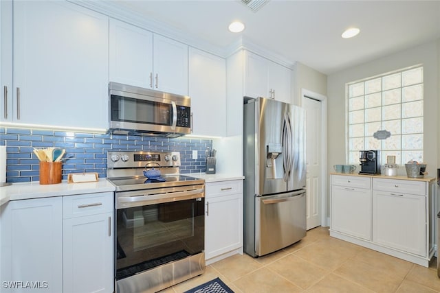 kitchen featuring white cabinets, light tile patterned flooring, backsplash, and appliances with stainless steel finishes