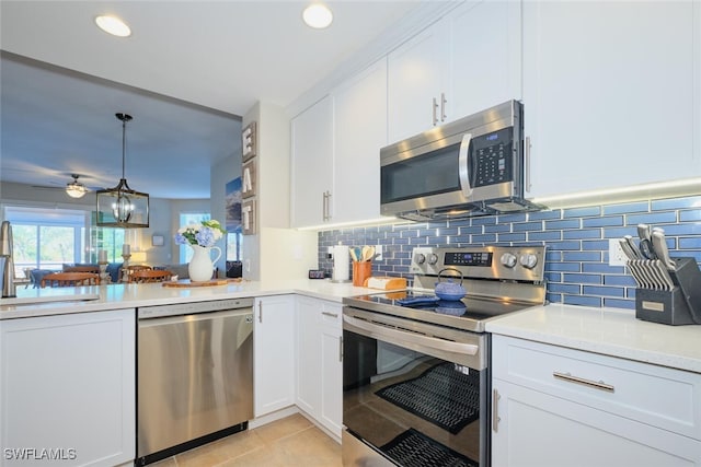 kitchen with pendant lighting, sink, light tile patterned floors, appliances with stainless steel finishes, and white cabinetry