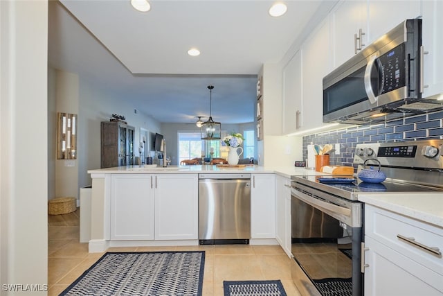 kitchen featuring light tile patterned floors, kitchen peninsula, pendant lighting, white cabinets, and appliances with stainless steel finishes