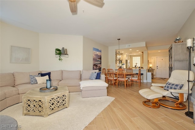 living room with wood-type flooring and ceiling fan with notable chandelier