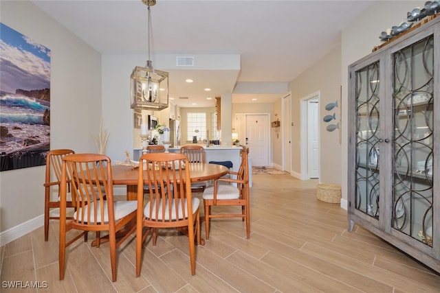 dining area with light wood-type flooring and an inviting chandelier