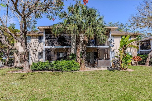 back of property with a sunroom and a yard