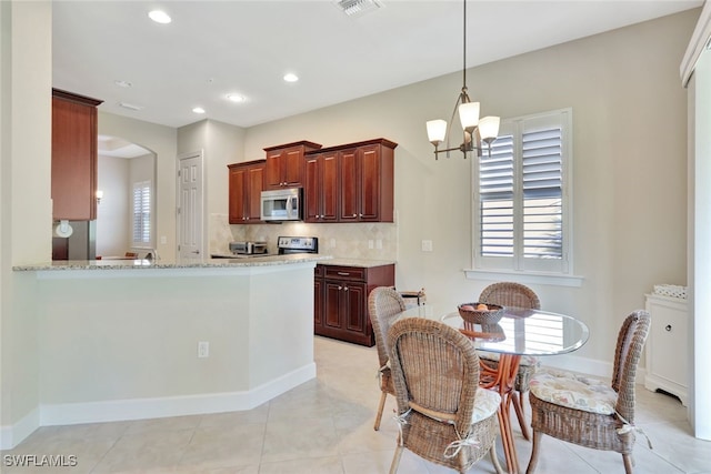 kitchen featuring an inviting chandelier, decorative backsplash, light tile patterned floors, kitchen peninsula, and stainless steel appliances