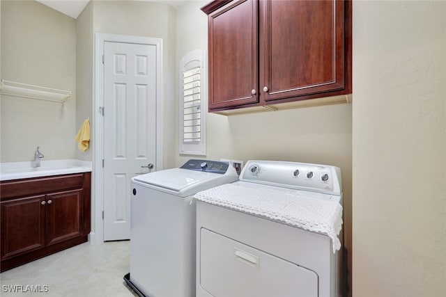 clothes washing area with washing machine and dryer, sink, and cabinets